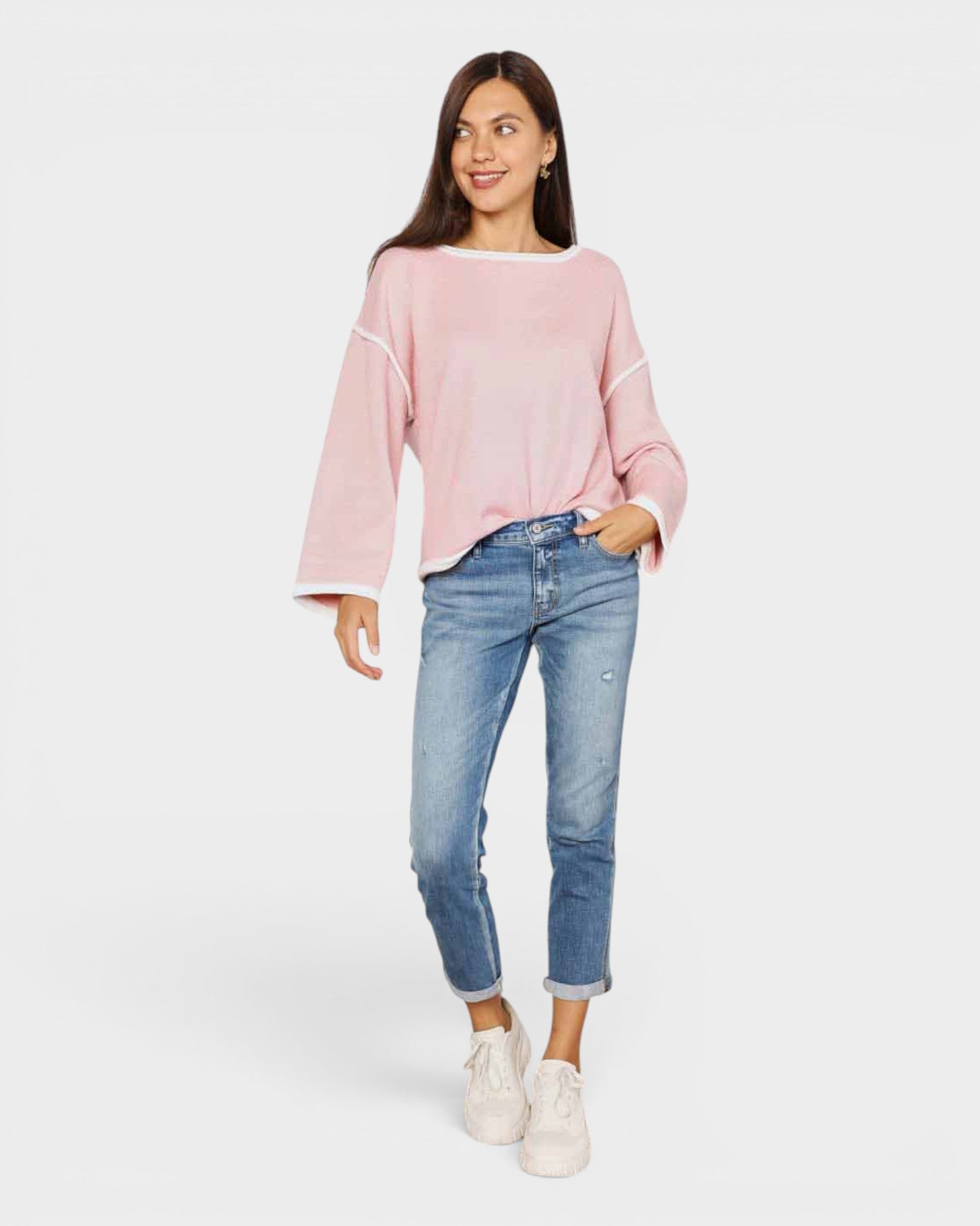 Woman wearing a pink sweater and blue jeans on a white background