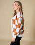 Woman wearing a checkered sweater with brown and white pattern against a beige background