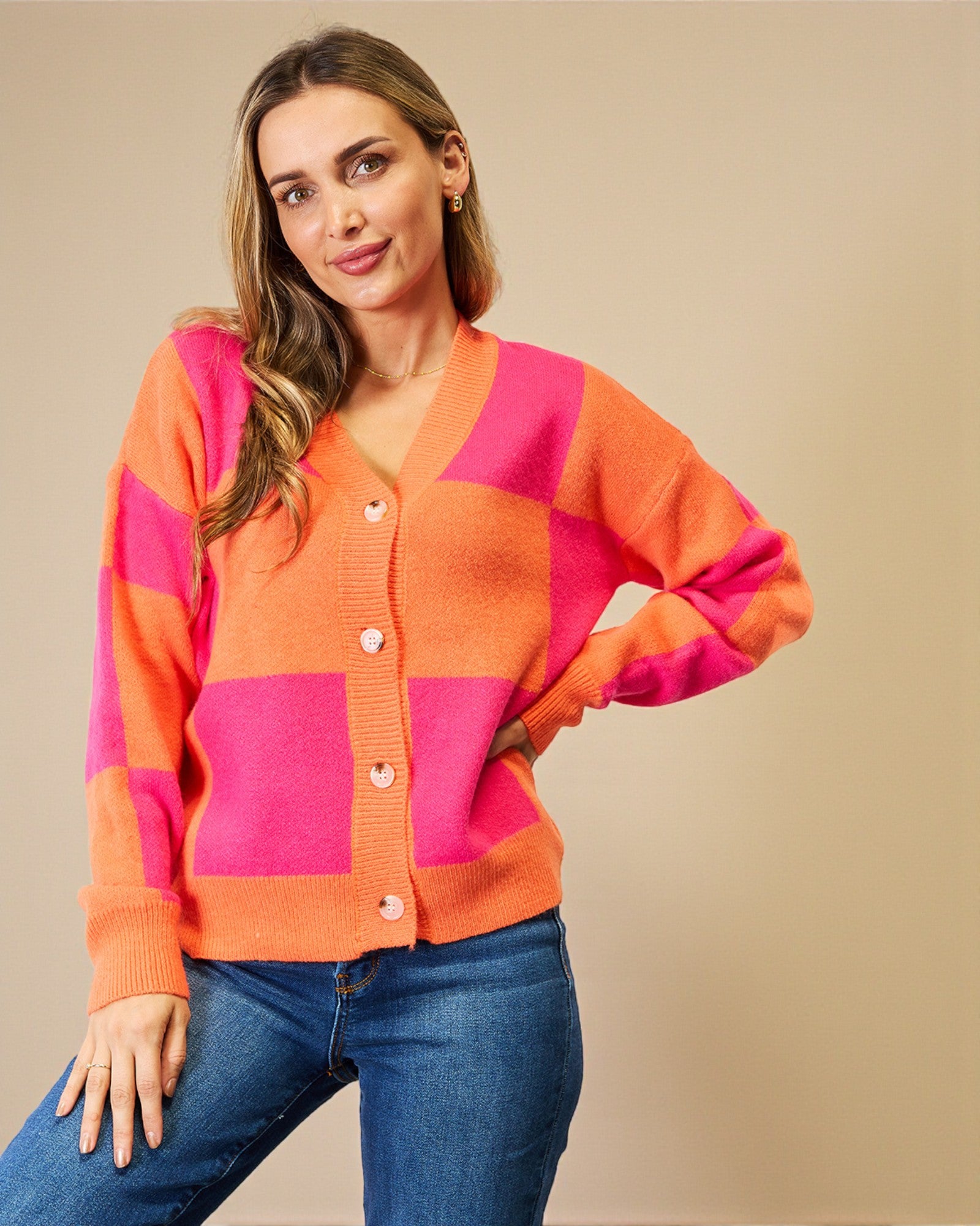 Woman wearing a pink and orange checkered cardigan against a beige background