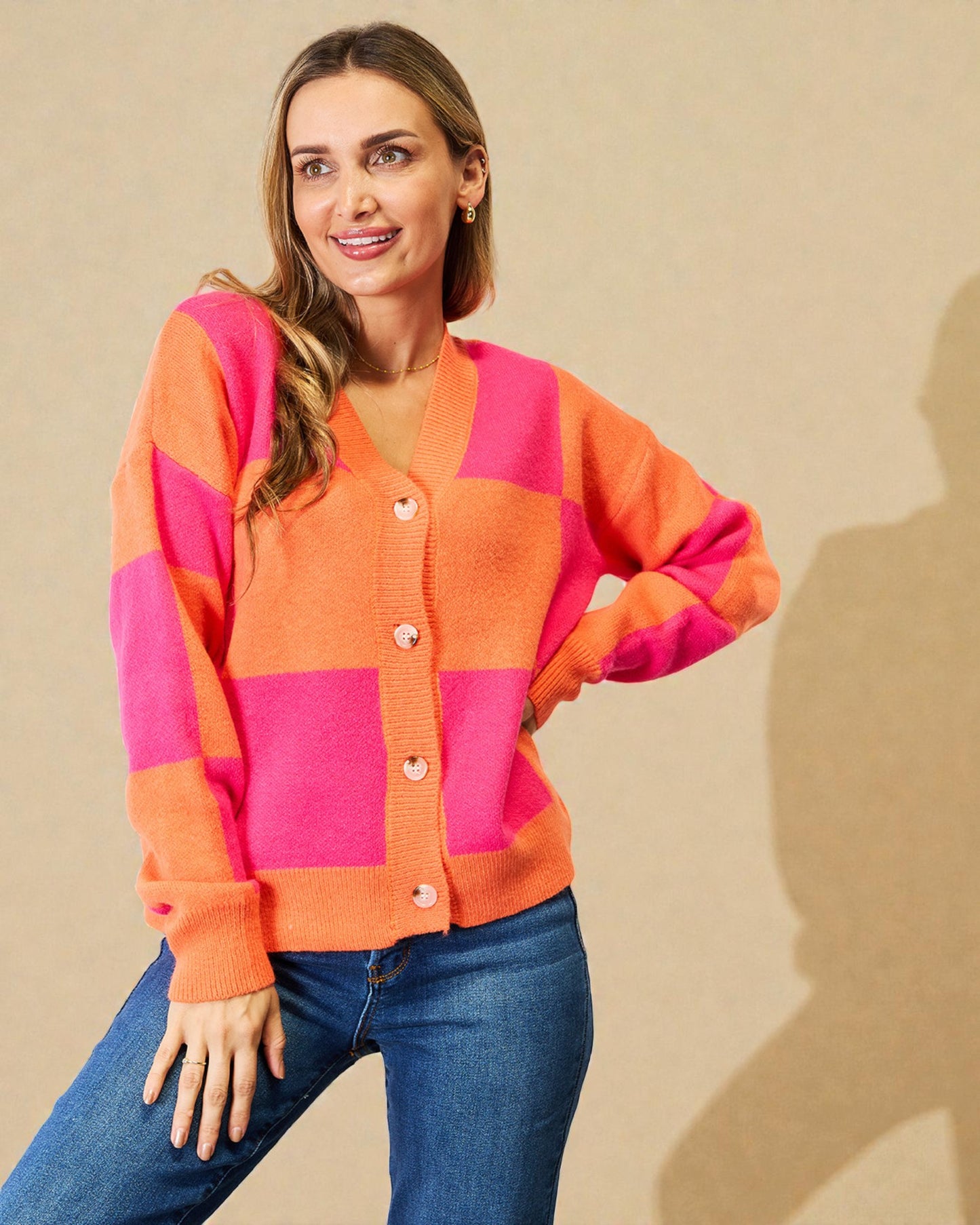 Woman wearing a pink and orange checkered cardigan against a beige background