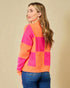 Woman wearing a colorful sweater with pink and orange squares on a beige background