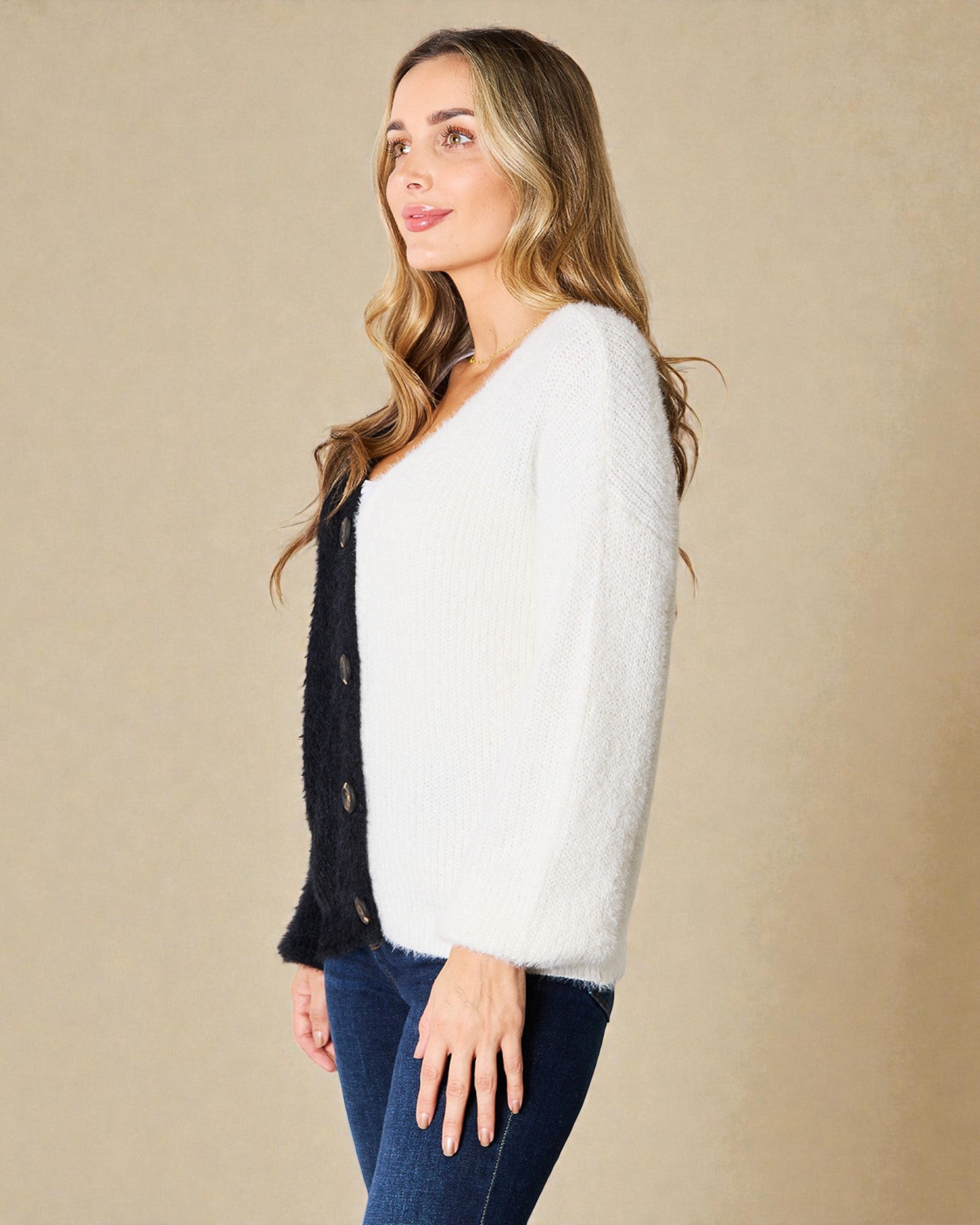 Woman wearing a white sweater over a black cardigan on a beige background