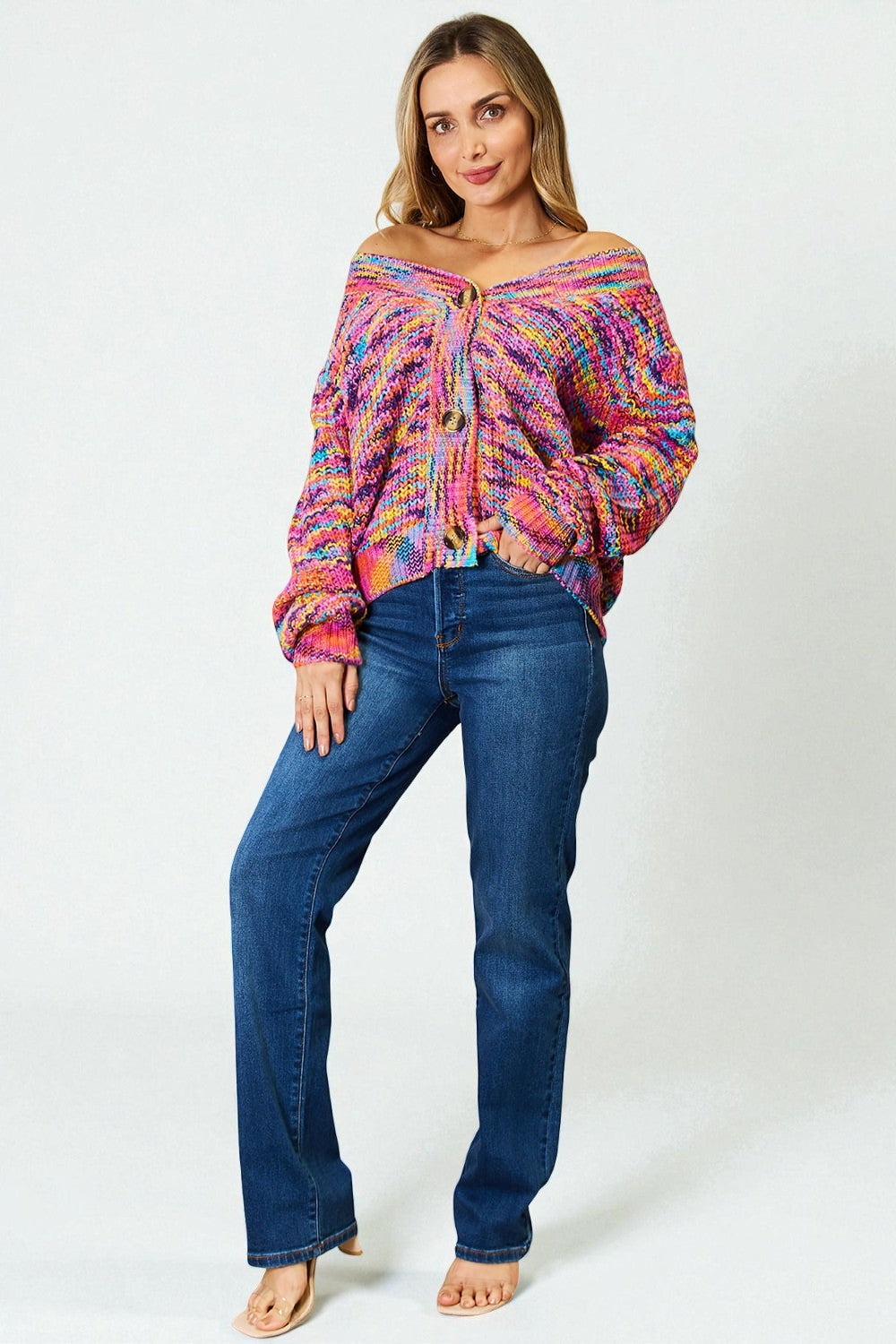 Woman wearing a colorful off-shoulder top and blue jeans on a white background