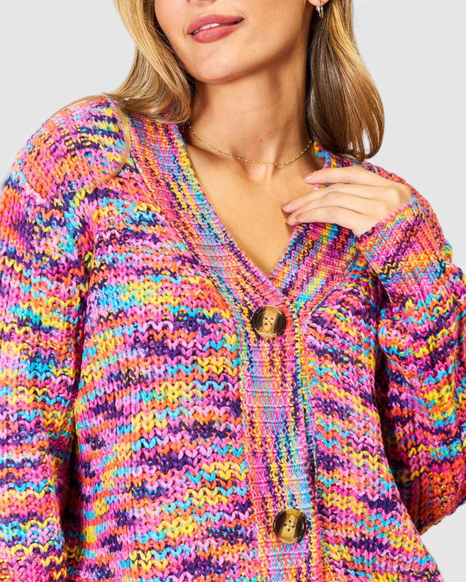 Multicolored knitted cardigan worn by a person on a light gray background