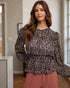 Woman wearing a patterned top and pink pants indoors