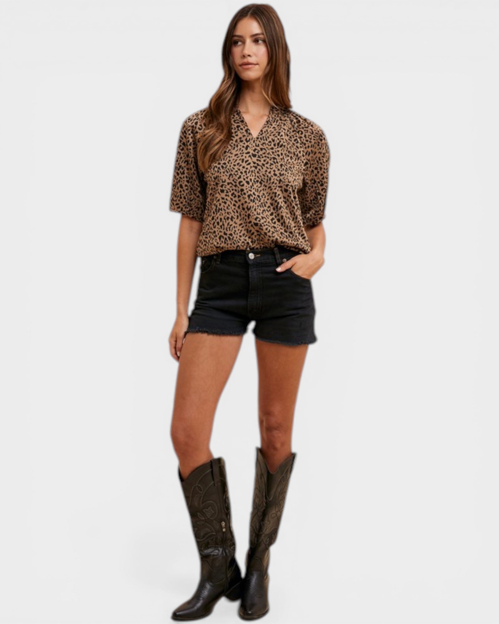 Woman wearing a leopard print top, black shorts, and brown boots on a white background