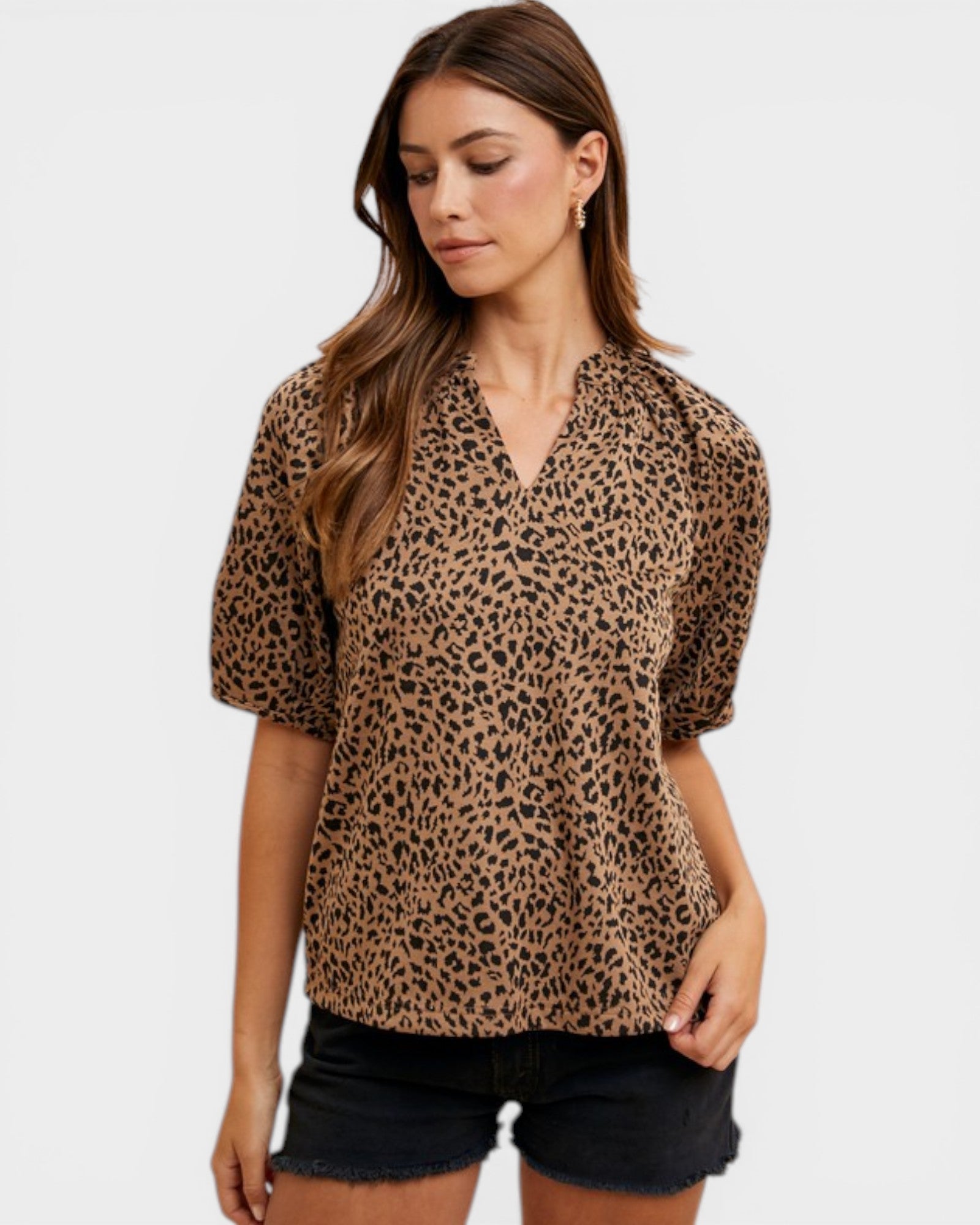 Woman wearing a leopard print blouse and black shorts on a white background