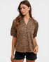 Woman wearing a leopard print blouse and black shorts on a white background
