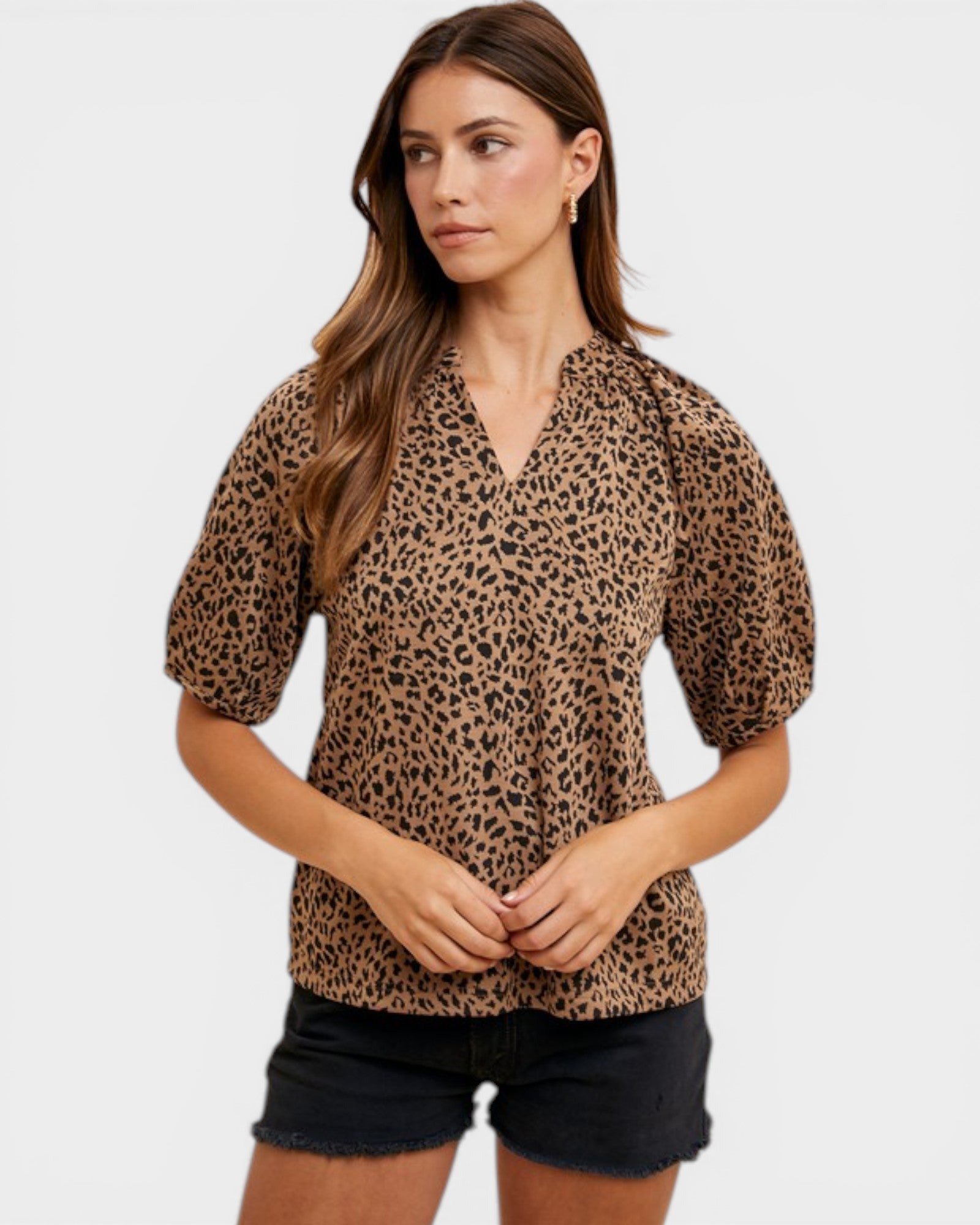 Woman wearing a leopard print blouse and black shorts on a white background