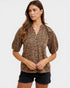Woman wearing a leopard print blouse and black shorts on a white background