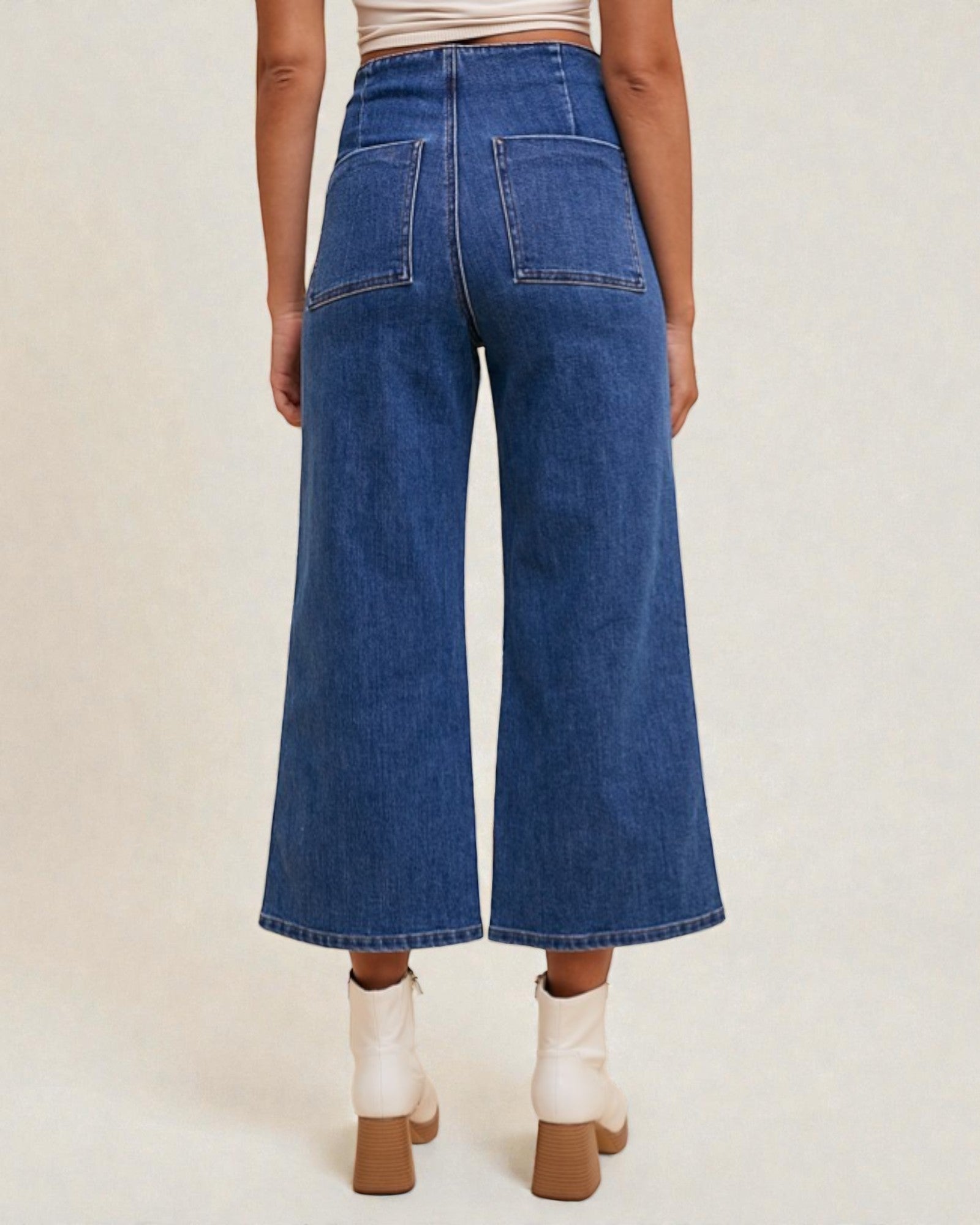 Person wearing blue wide-leg jeans on a plain background