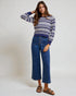 Woman wearing a striped sweater and blue jeans against a white background