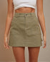 Person wearing a green skirt with a plain background