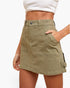 An olive green cargo-style mini skirt with front patch pockets and side cargo pockets, shown on a model against a plain white background.