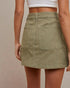 Person wearing a green skirt with a neutral background