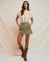 Woman wearing a striped top, green skirt, and brown boots against a plain background
