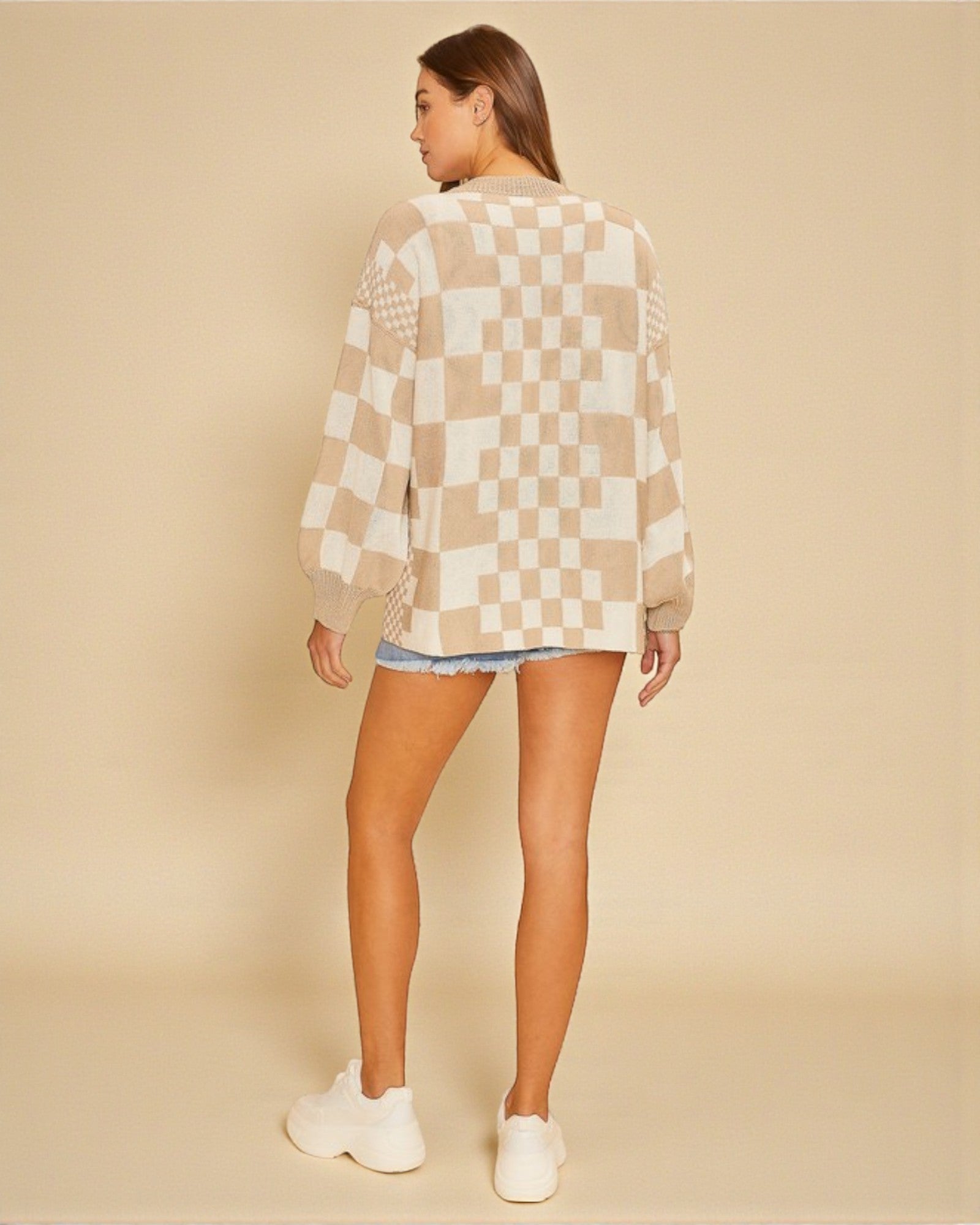 Person wearing a checkered sweater and shorts on a beige background