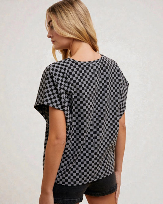 Woman wearing a black and white checkered top with a plain background