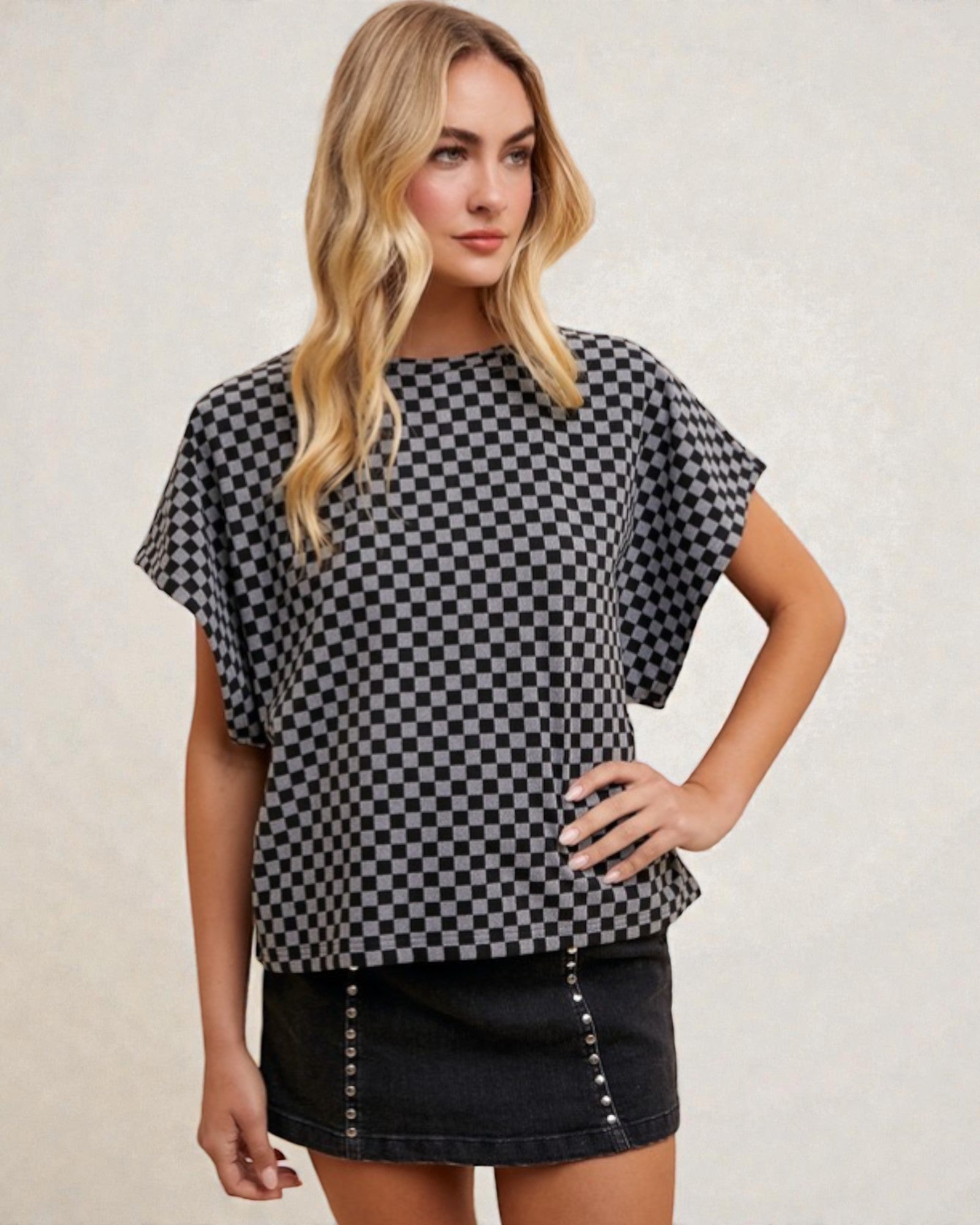 Woman wearing a black and white checkered top with a plain background