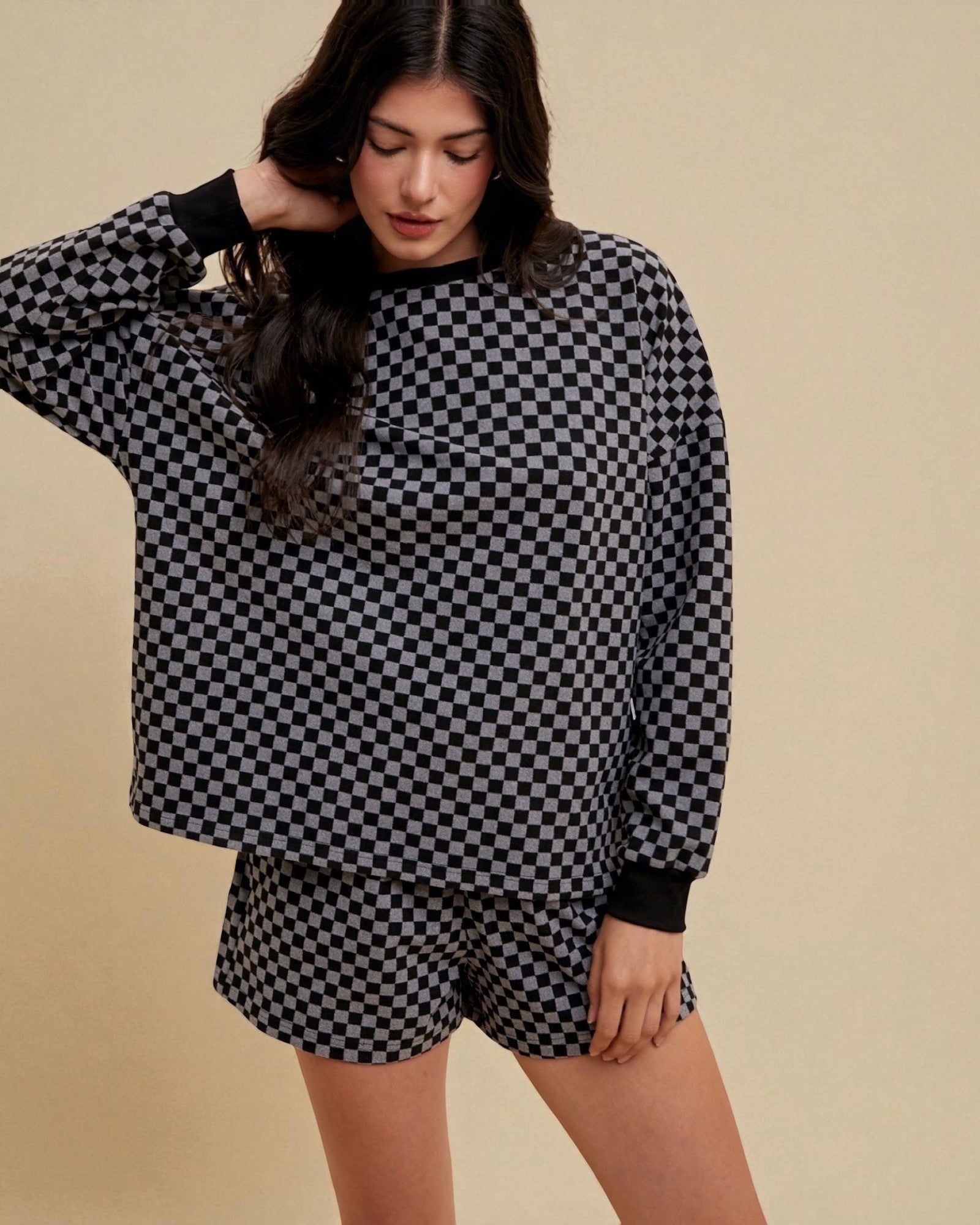 Person wearing a black and white checkered outfit on a beige background