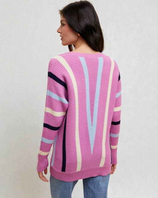 Woman wearing a pink sweater with colorful stripes on a plain background