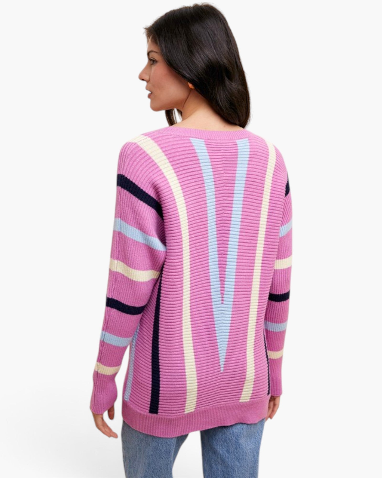 A woman shown from the back wearing a pink ribbed knit sweater with vertical stripes in cream, light blue, and black, paired with blue jeans against a plain white background.