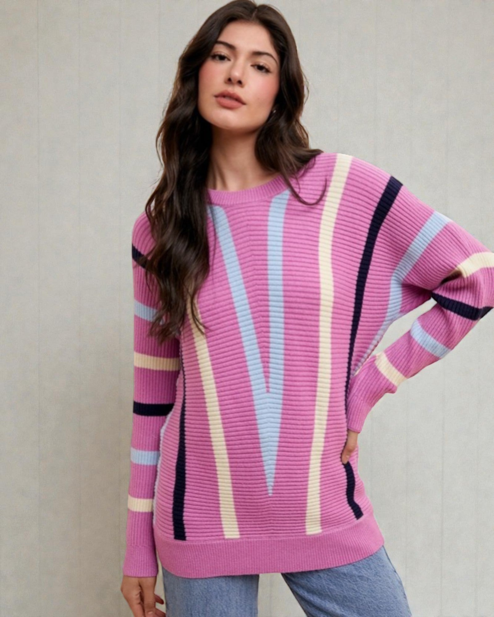 Woman wearing a pink sweater with colorful stripes against a plain background