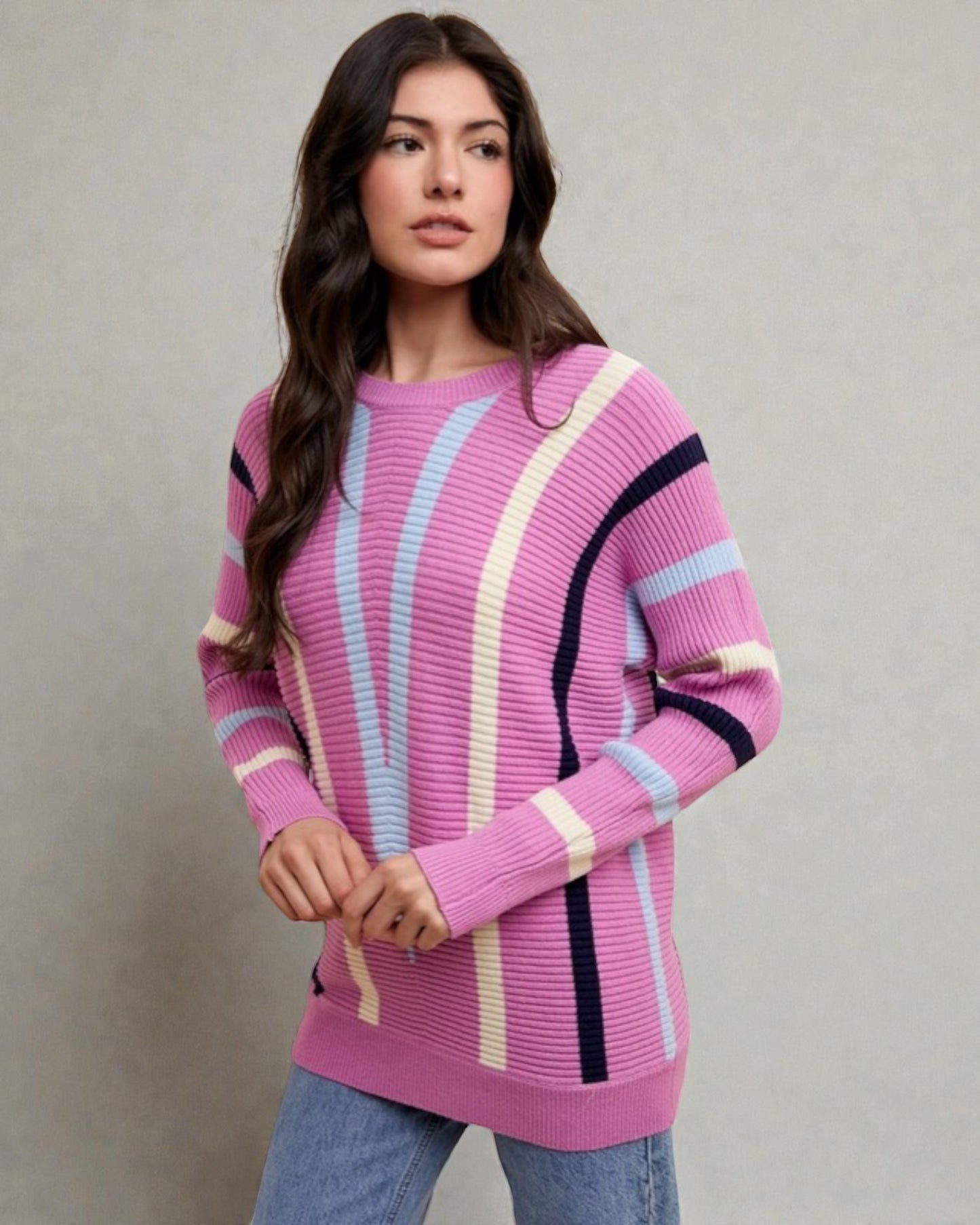 Woman wearing a pink sweater with colorful stripes against a neutral background