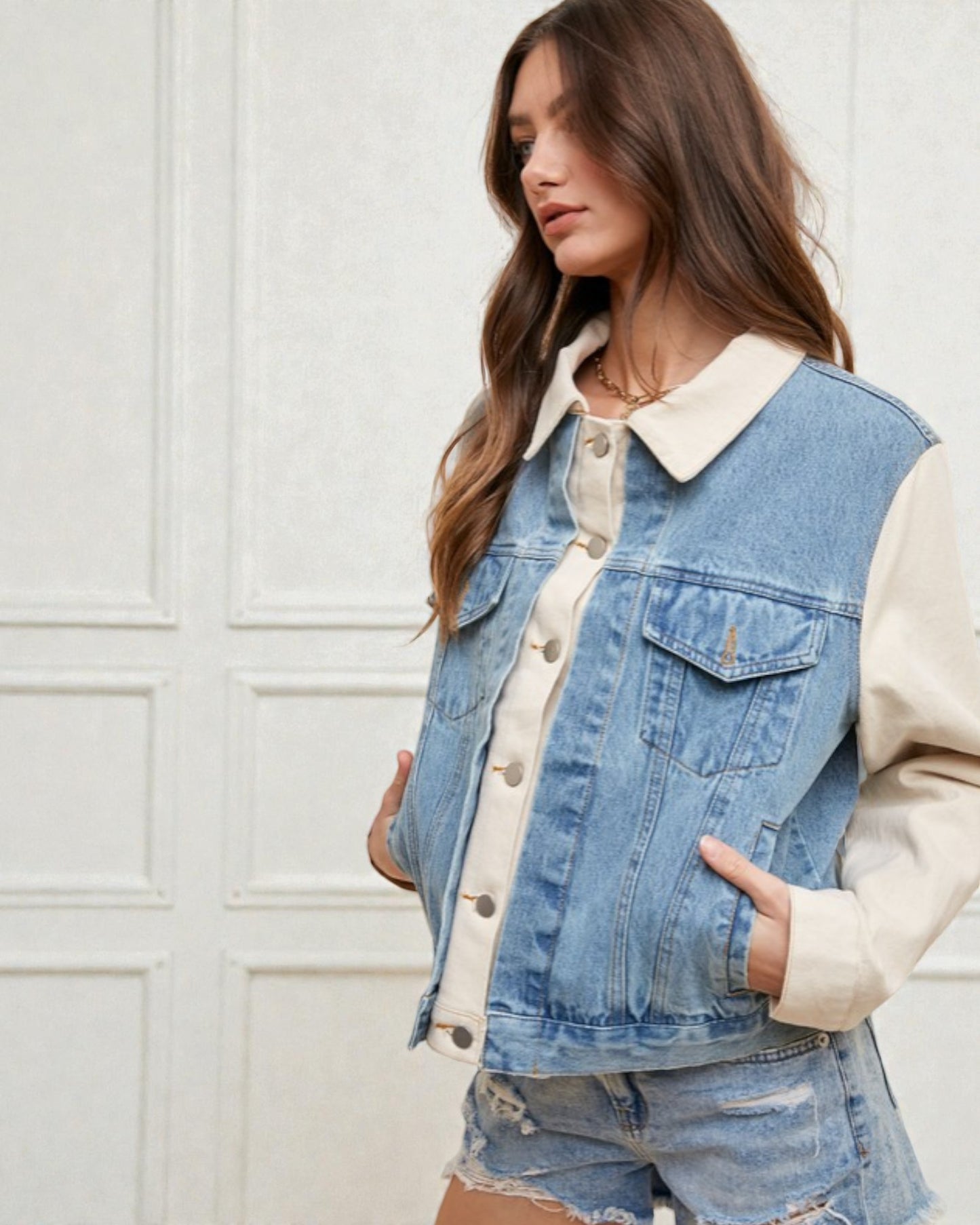 Woman wearing a denim vest over a white shirt with a neutral background