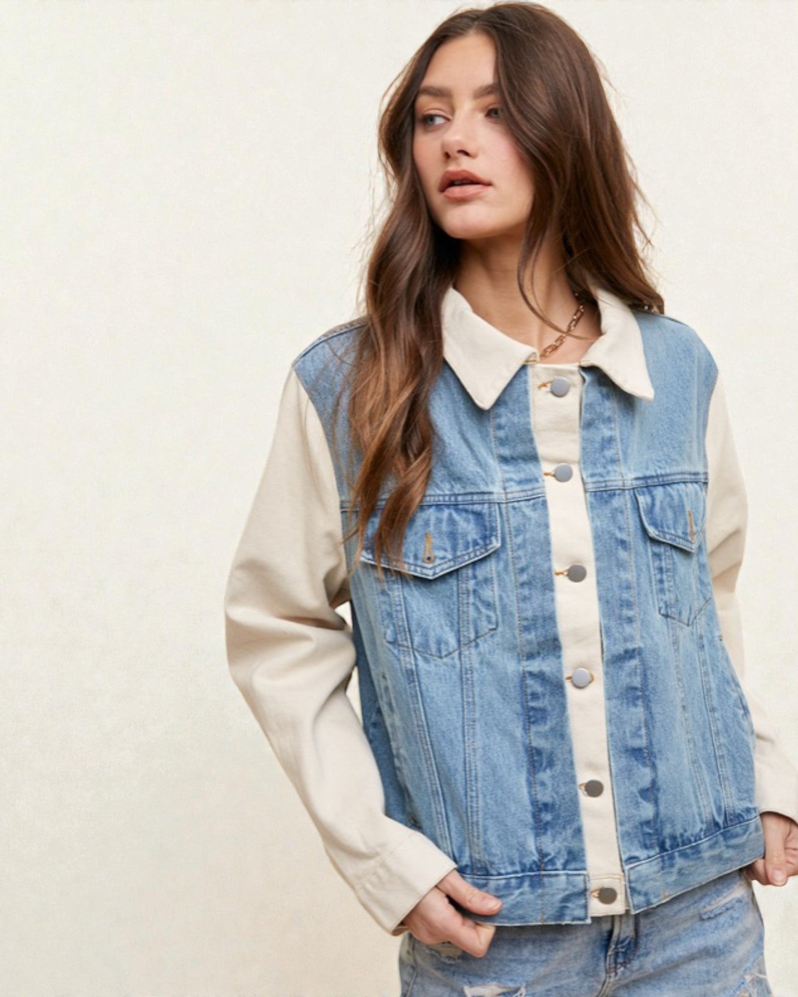Woman wearing a denim and cream jacket on a plain background