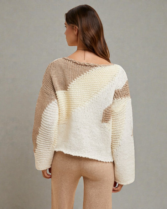 Woman wearing a beige and white patterned sweater against a plain background