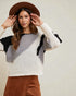 Woman wearing a patterned sweater and brown hat against a plain background