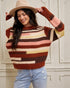 Woman wearing a colorful striped sweater and beige hat indoors.