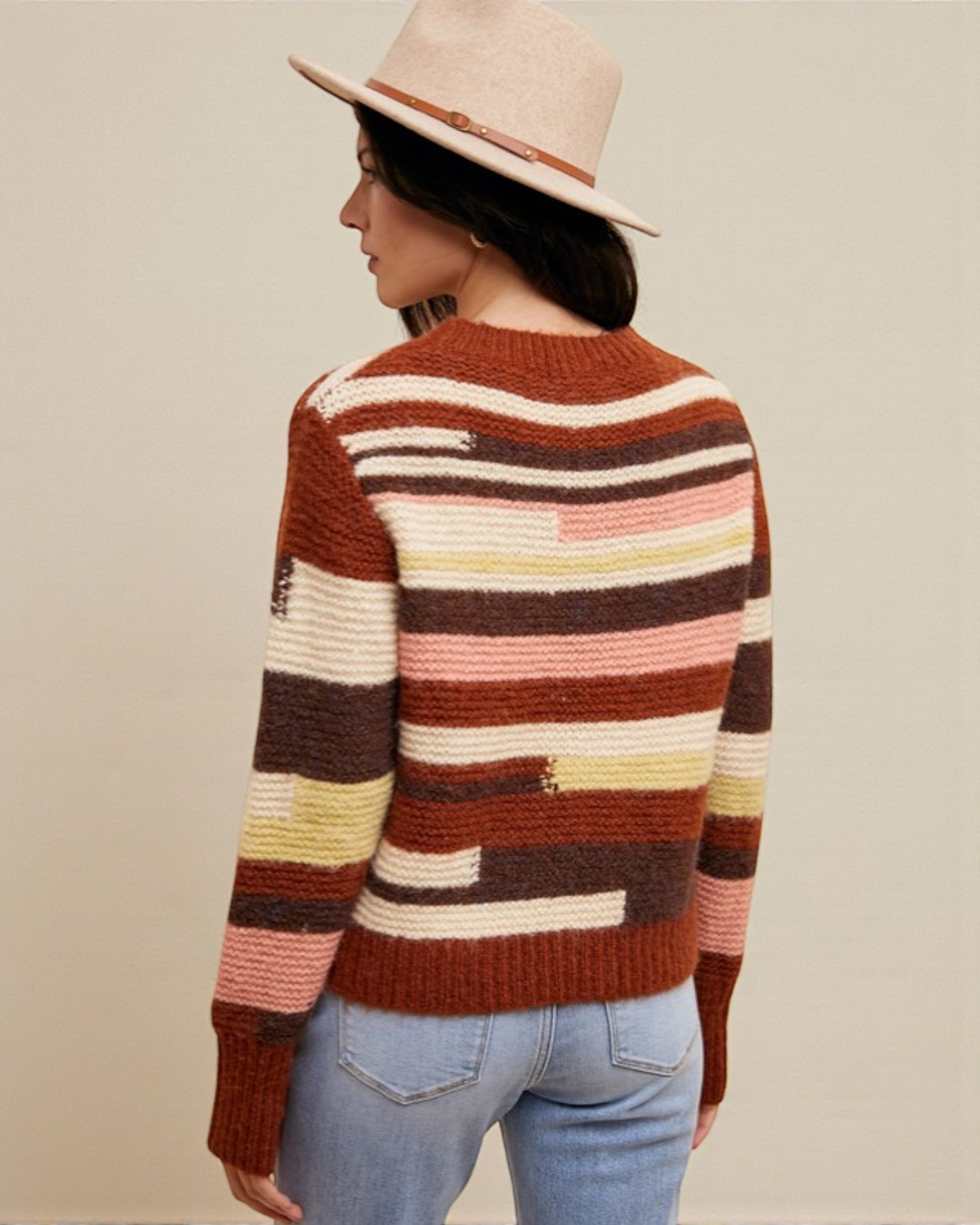 Person wearing a colorful striped sweater and hat on a beige background