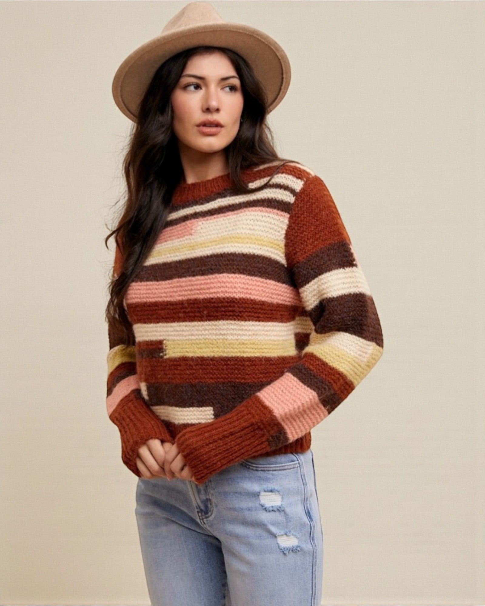 Woman wearing a striped sweater and hat against a plain background