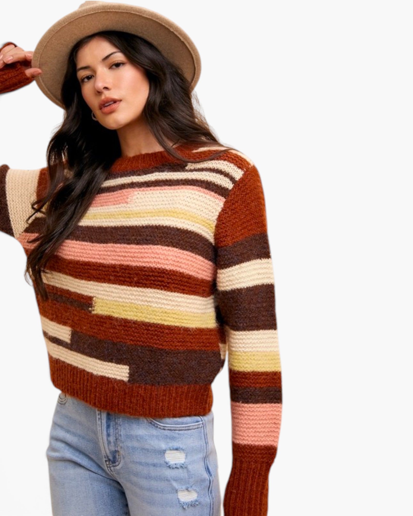 A woman wearing a brown, rust, and cream striped knit sweater, a beige wide-brim hat, and light-wash distressed jeans, photographed against a plain white background.