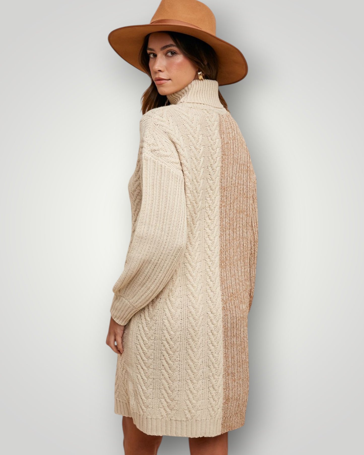 Woman wearing a beige cable knit sweater and brown hat against a white background