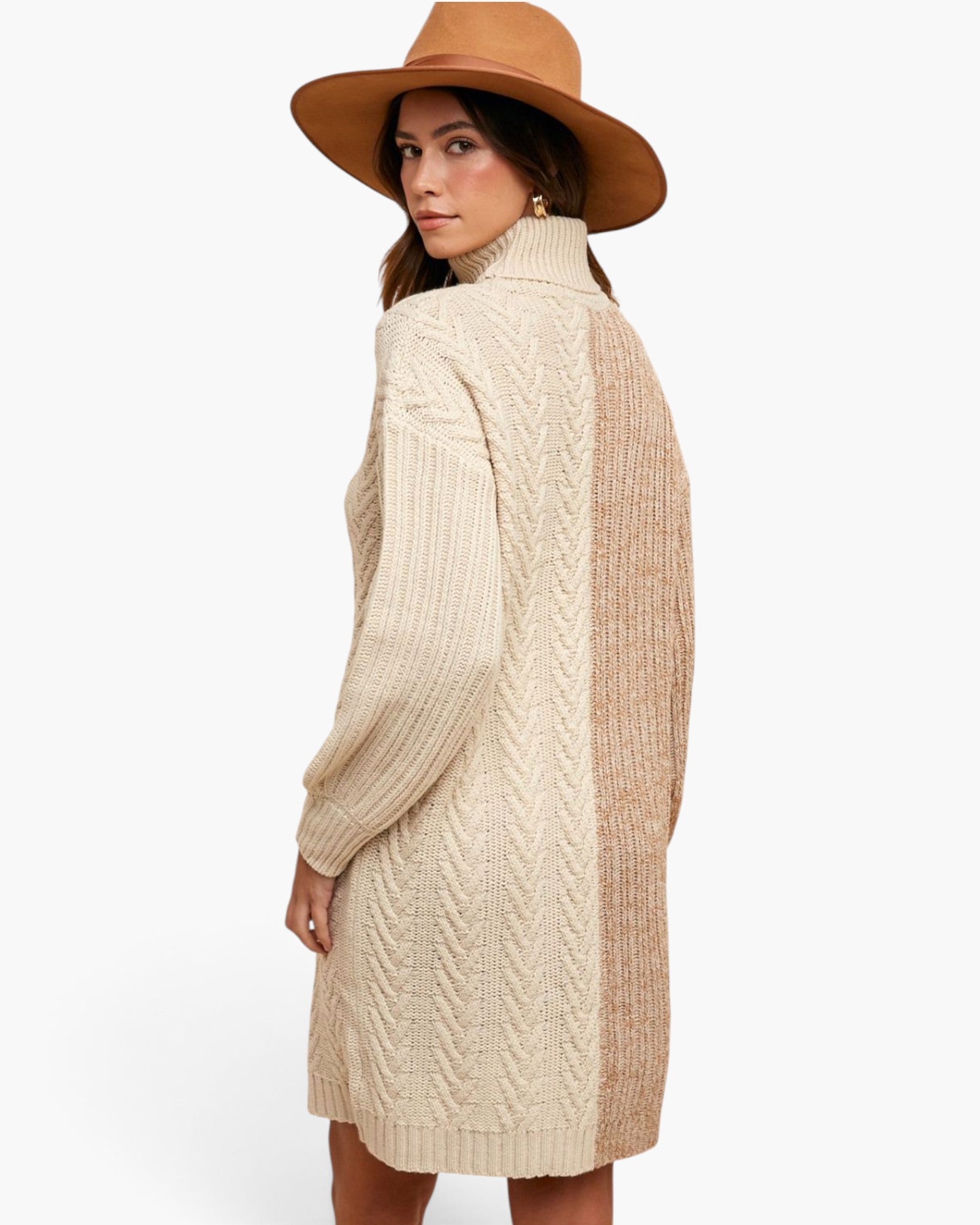 A woman wearing a cream and beige cable-knit turtleneck sweater dress, paired with a brown wide-brim hat, shown from a three-quarters back view against a plain white background.
