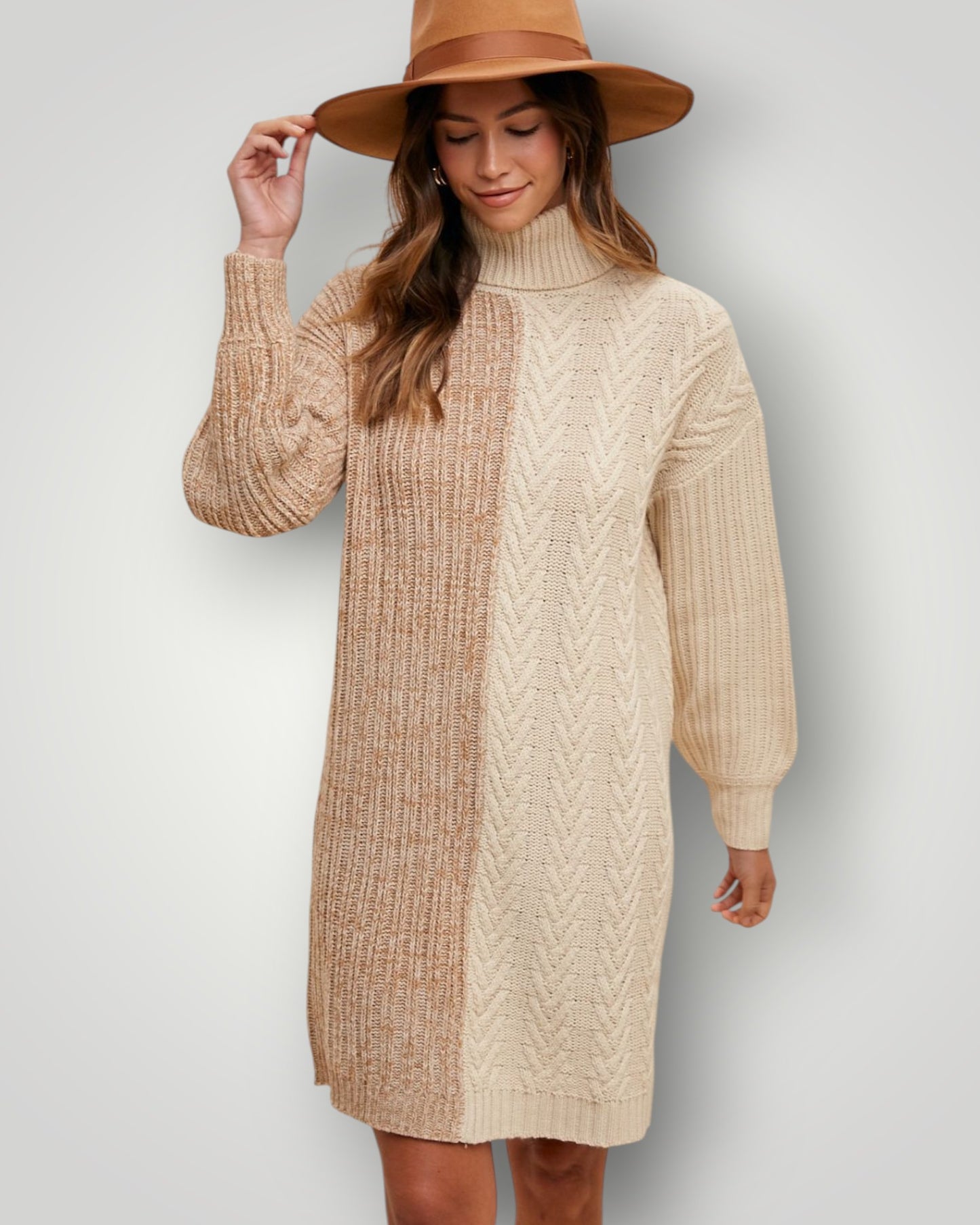 Woman wearing a beige cable knit sweater dress and brown hat against a plain background