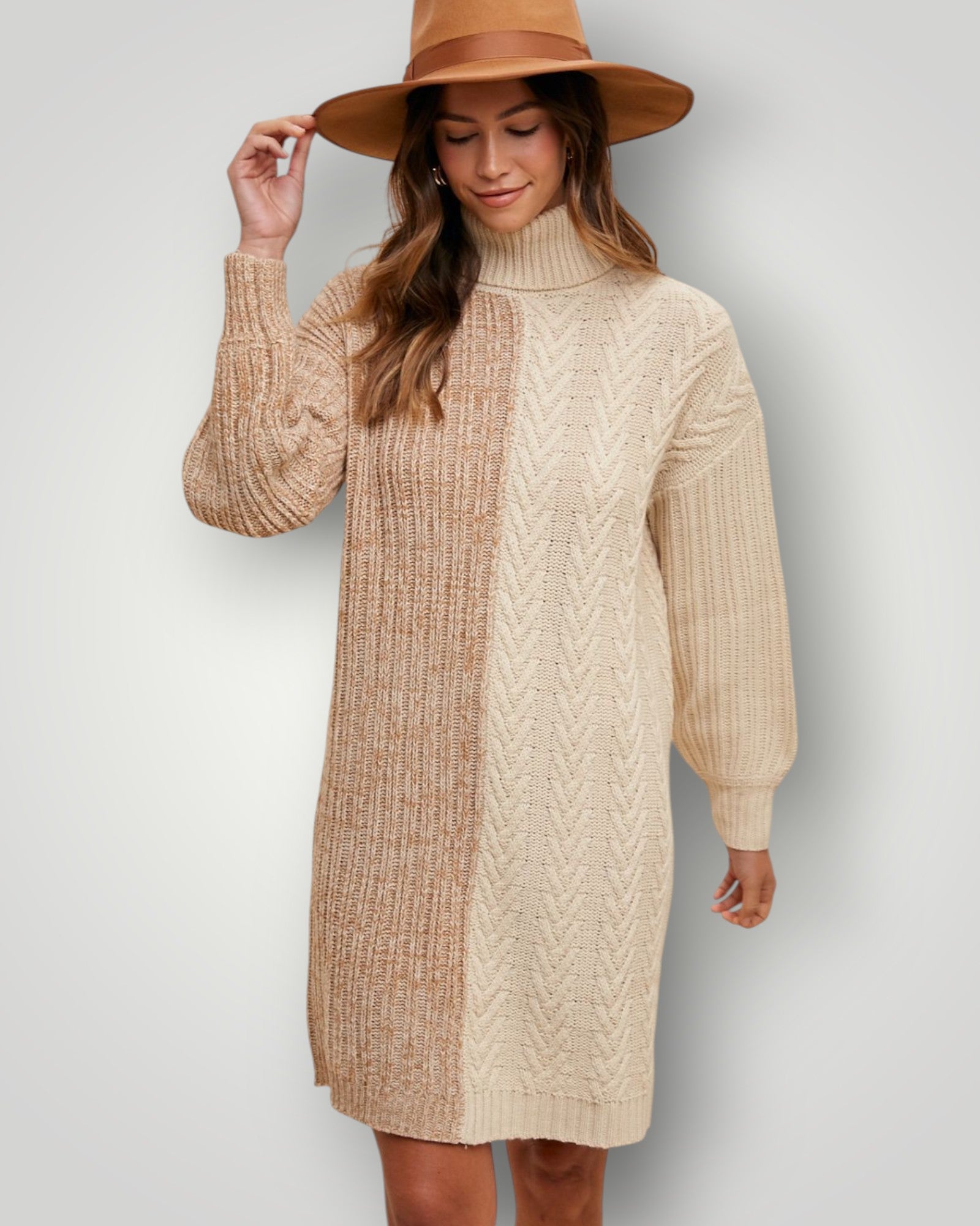 Woman wearing a beige cable knit sweater dress and brown hat against a plain background