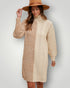 Woman wearing a beige cable knit sweater dress and brown hat against a plain background