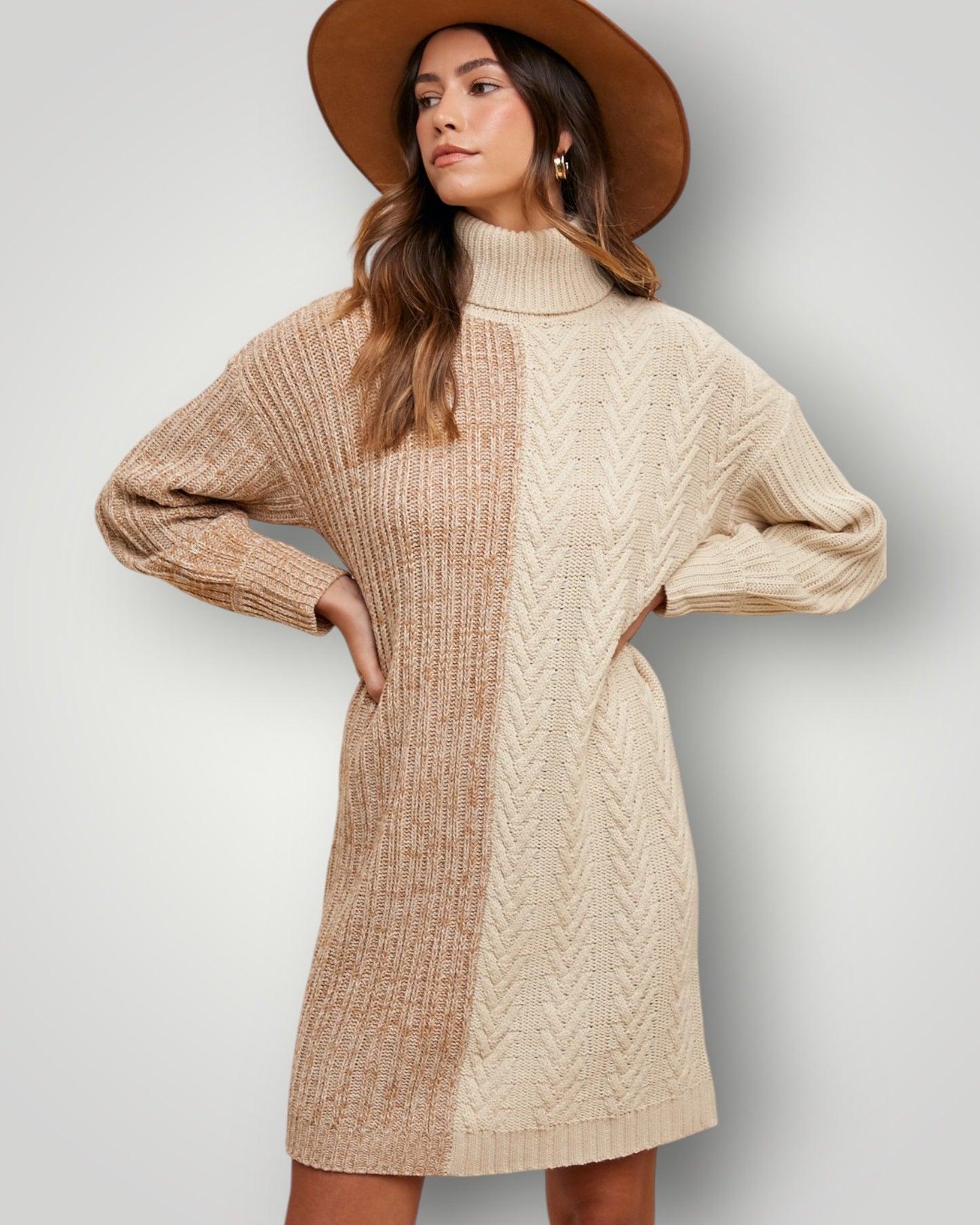 Woman wearing a beige cable knit sweater dress with a brown hat on a light gray background