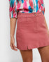 Person wearing a colorful shirt and pink skirt on a white background