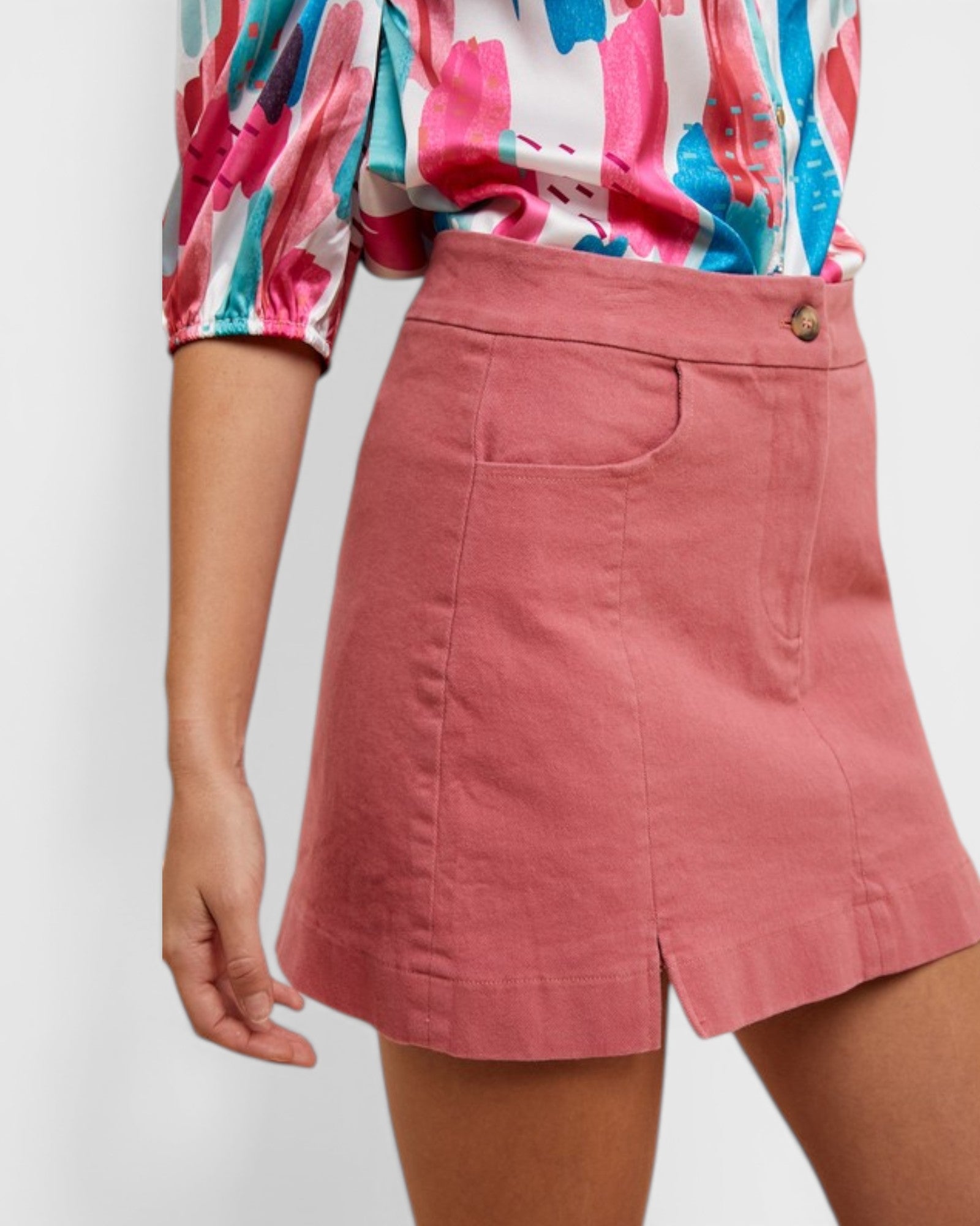 Person wearing a colorful blouse and pink skirt on a white background