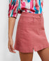 Person wearing a colorful blouse and pink skirt on a white background