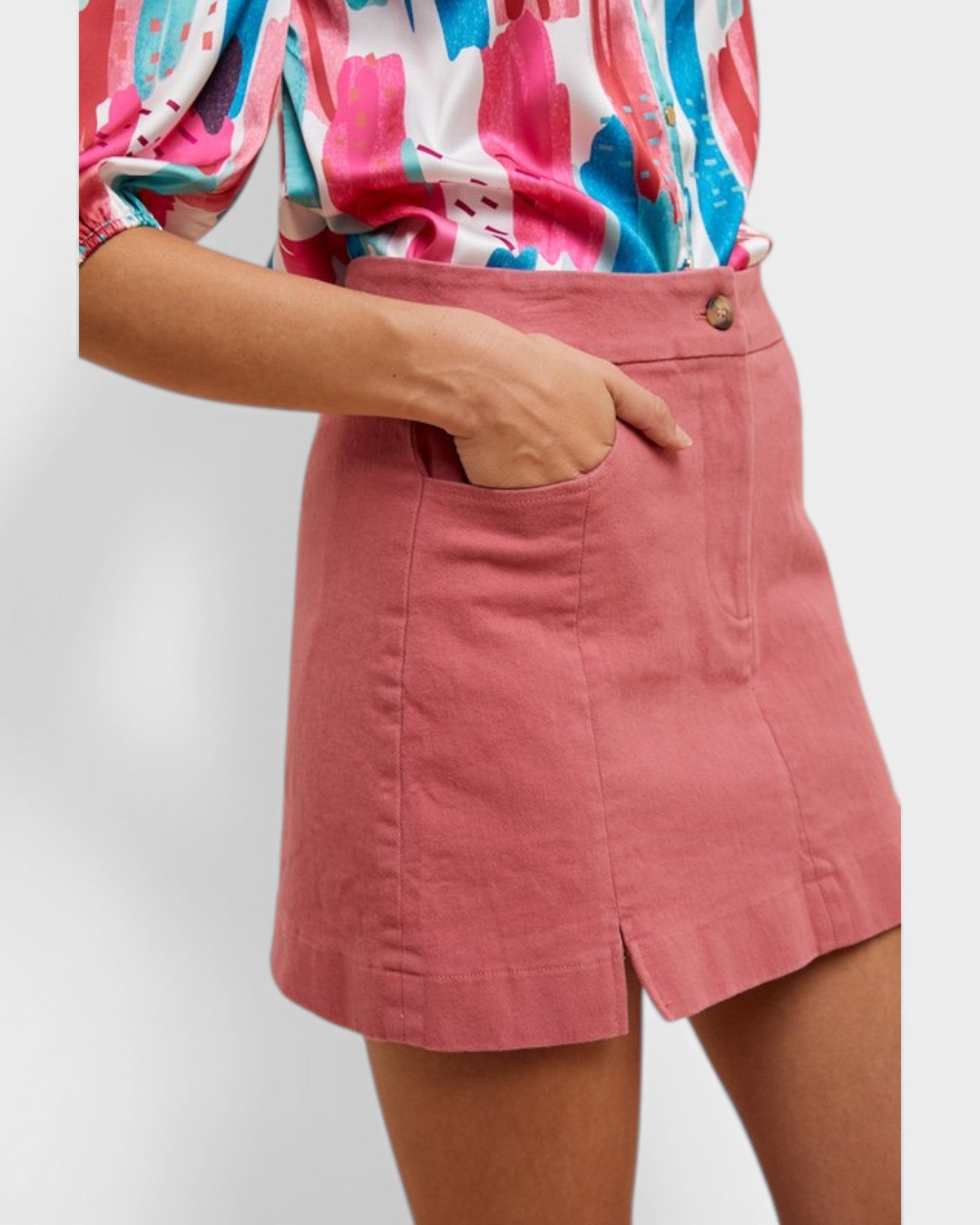 Person wearing a colorful shirt and pink skirt on a plain background