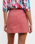 Person wearing a colorful blouse and pink skirt on a white background