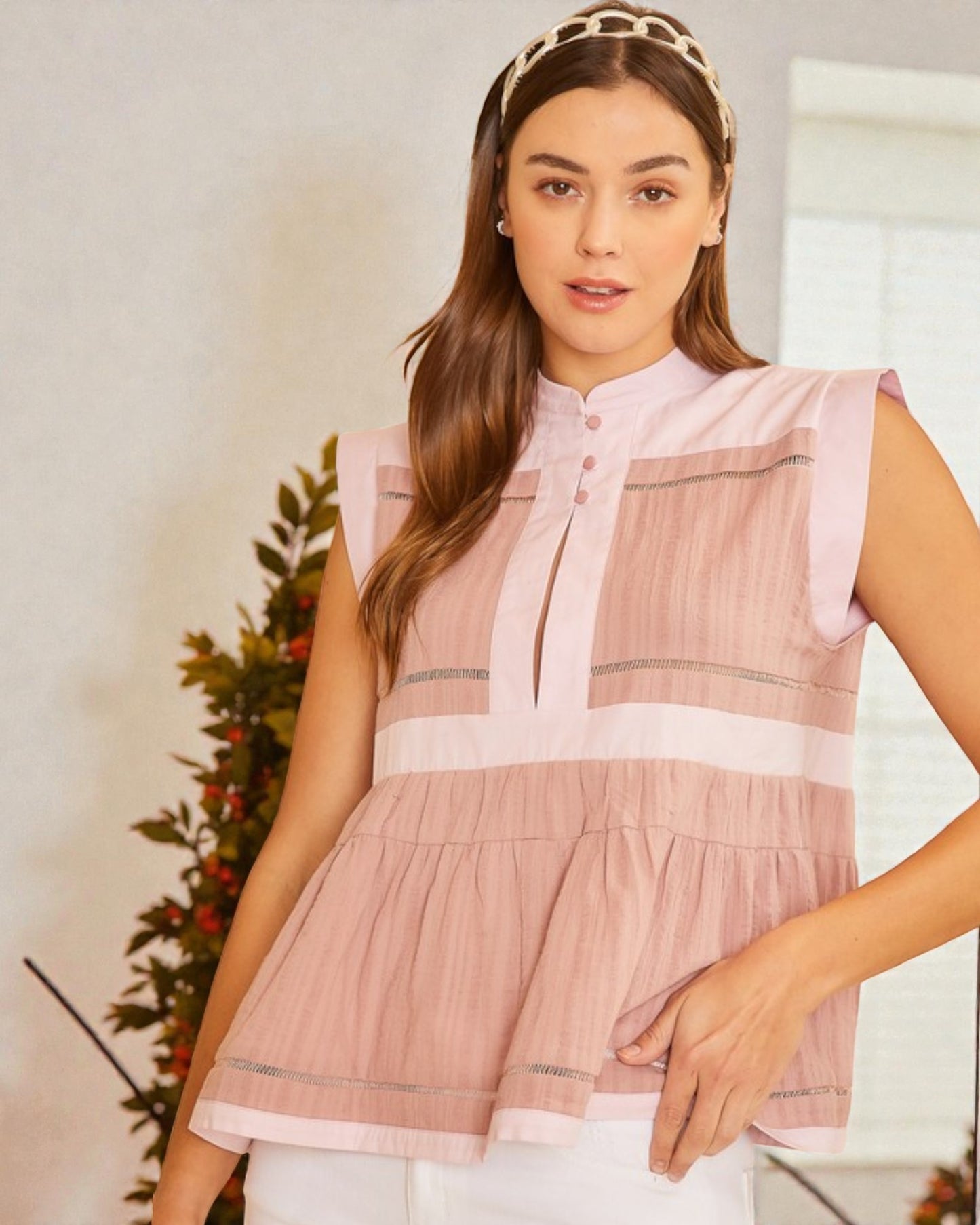 Woman wearing a pink sleeveless top with a neutral background