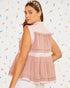 Woman wearing a pink sleeveless top with a white background and colorful confetti-like patterns.