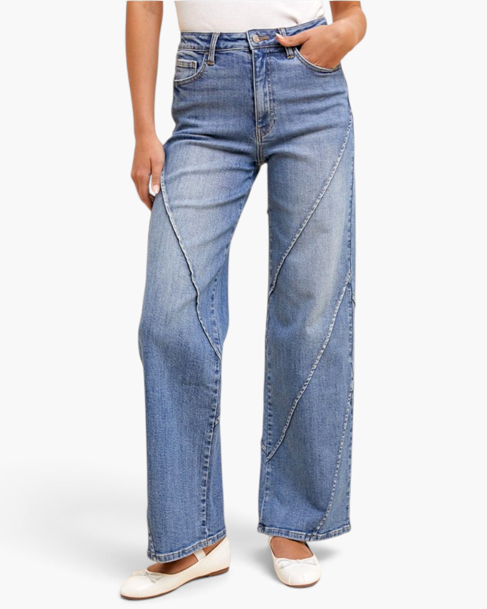 A model wearing a pair of light blue wide-leg denim jeans with diagonal contrast stitching details, paired with white flats, shown against a plain white studio background.